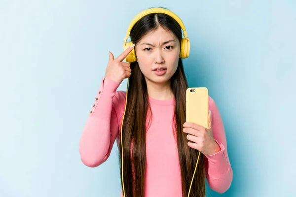 Jovem Mulher Asiática Ouvindo Música Isolada Fundo Azul Mostrando Gesto — Fotografia de Stock