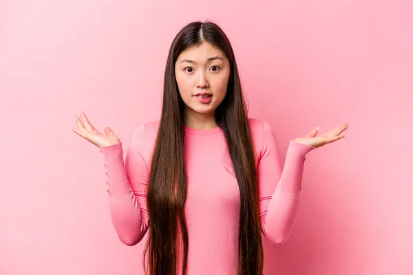 年轻的中国女人在粉红的背景上孤立无援 困惑而怀疑地耸了耸肩以保持复制的空间 — 图库照片