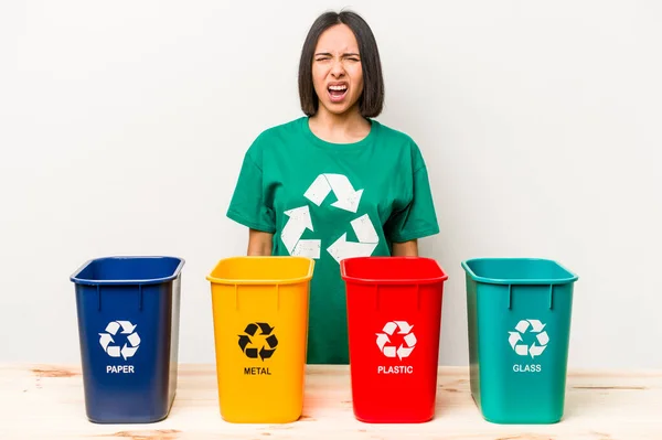 Young hispanic woman recycling isolated on white background screaming very angry and aggressive.