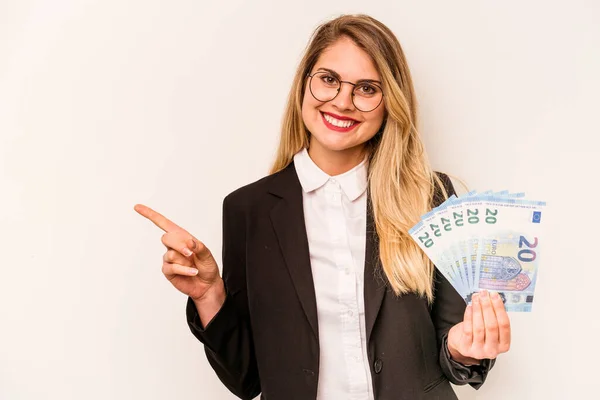 白地に孤立した紙幣を持っている若い実業家の白人女性は笑顔と脇を指差して 空白のスペースで何かを示す — ストック写真