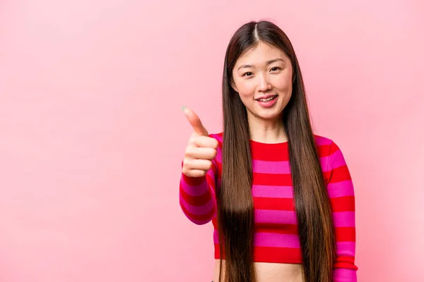 年轻的中国女人在粉红的背景上孤独地微笑着 竖起大拇指 — 图库照片