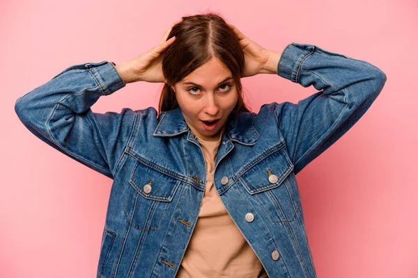 Pembe arka planda izole edilmiş genç beyaz kadın çığlık atıyor, çok heyecanlı, tutkulu, bir şeyden memnun..