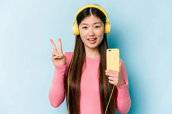 Joven Asiática Escuchando Música Aislada Sobre Fondo Azul Alegre Despreocupada —  Fotos de Stock