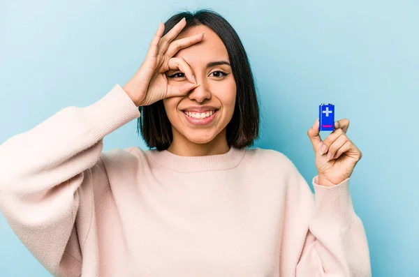若いですヒスパニック女性保持電池隔離上の青背景励起維持Okジェスチャー上の目 — ストック写真