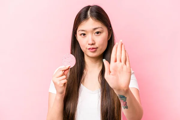 年轻的亚洲女人手握粉红背景的面部海绵 伸出来的手显示出停止的迹象 阻止了你 — 图库照片
