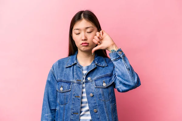 年轻的中国女人在粉红的背景上表现出不喜欢的姿态 低垂了大拇指 不同意的概念 — 图库照片