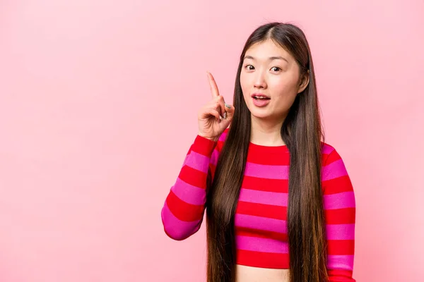 在粉色背景上被隔离的年轻中国女人用手指表现出第一位 — 图库照片