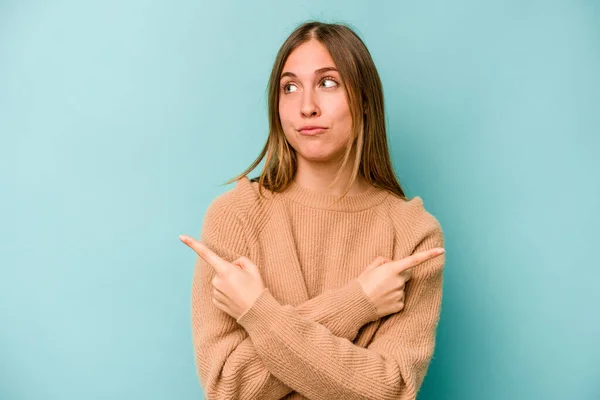 Jonge Blanke Vrouw Geïsoleerd Blauwe Achtergrond Punten Zijwaarts Probeert Kiezen — Stockfoto