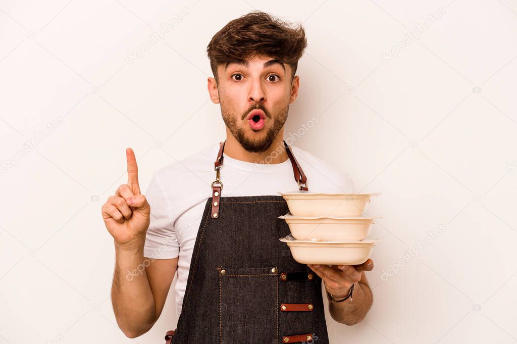 Young hispanic clerk man holding a tupperware isolated on white background having some great idea, concept of creativity.