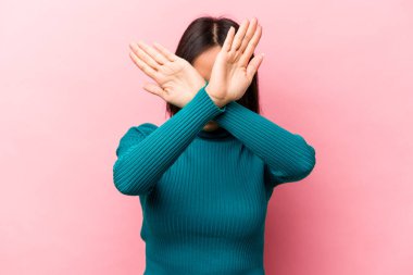 Pembe arka planda izole edilmiş genç İspanyol kadın iki kolu çapraz tutuyor, inkar kavramı.