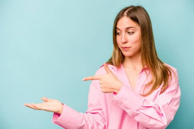 Mavi arka planda izole edilmiş beyaz bir kadın. Elinde palmiye ağacının fotokopisini tutarken heyecanlı..