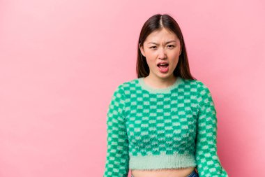 Pembe arka planda izole edilmiş genç bir Çinli kadın çok kızgın, öfkeli ve sinirli bir şekilde bağırıyor..