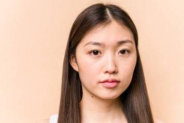 Genç bir Asyalı kadın bej arka planda izole edilmiş.