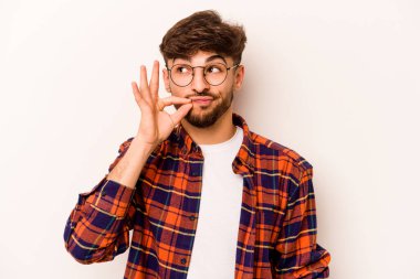 Beyaz arka planda izole edilmiş genç İspanyol adam parmakları dudaklarında bir sır saklıyor..