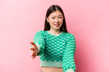 Pembe arka planda izole edilmiş genç Çinli kadın hoş bir yüz ifadesi sergiliyor..