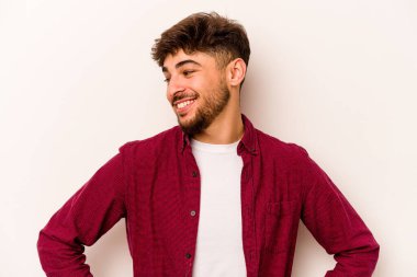 Beyaz arka planda izole edilmiş genç İspanyol bir adam. Kendine güveniyor. Kalçaları tutuyor..