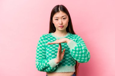 Pembe arka planda izole edilmiş genç Çinli kadın bir mola hareketi gösteriyor..