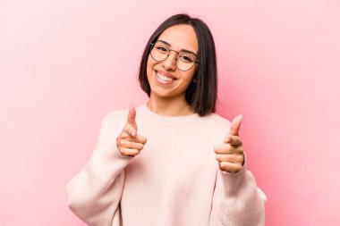 Pembe arka planda izole edilmiş genç İspanyol kadın. Önü işaret eden neşeli gülümsemeler..