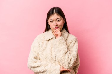 Genç Çinli kadın pembe arka planda izole edilmiş düşünüyor, yukarı bakıyor, yansıtıyor, düşünüyor, hayal kuruyor..