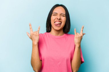 Mavi arka planda izole edilmiş genç İspanyol kadın boynuzlarını devrim konsepti olarak gösteriyor..