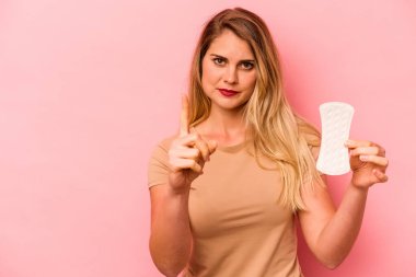 Elinde hijyenik peçete tutan beyaz bir kadın pembe arka planda bir numarayı parmağıyla gösteriyor..