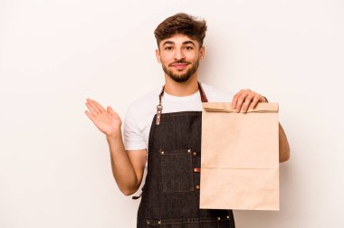 Beyaz arka planda izole edilmiş bir çanta tutan genç İspanyol tezgahtar bir avuç içinde fotokopi alanı ve belinde başka bir el tutuyor..