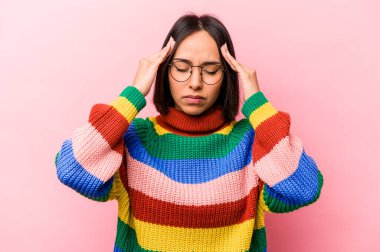 Genç İspanyol kadın pembe arka planda izole edilmiş tapınaklara dokunuyor ve baş ağrısı çekiyor..