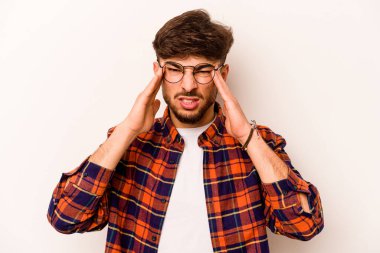 Beyaz arka planda izole edilmiş genç İspanyol adam tapınaklara dokunuyor ve baş ağrısı çekiyor..