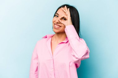 Latin kökenli genç bir kadın mavi arka planda izole edilmiş. Heyecanlı..