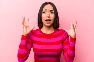 Genç İspanyol kadın pembe arka planda izole edilmiş gökyüzüne haykırıyor, yukarı bakıyor, hayal kırıklığına uğramış..