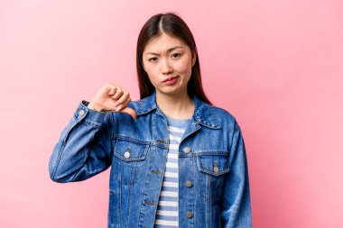 Pembe arka planda izole edilmiş genç Çinli kadın baş parmağını aşağı gösteriyor, hayal kırıklığı konsepti..