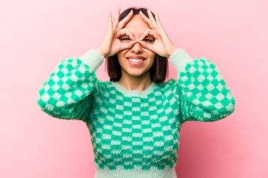 Pembe arka planda izole edilmiş genç İspanyol kadın gözlerinde sorun olmadığını gösteriyor.