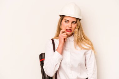 Miğferli ve elinde planları olan genç bir mimar kadın beyaz arka planda izole edilmiş bir şekilde bir şeyin fotokopi odasına baktığını düşünüyor..