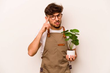 Genç bahçıvan İspanyol bir adam beyaz arka planda izole edilmiş bir bitki tutuyor işaret parmağıyla yaptığı hayal kırıklığı jestini gösteriyor..