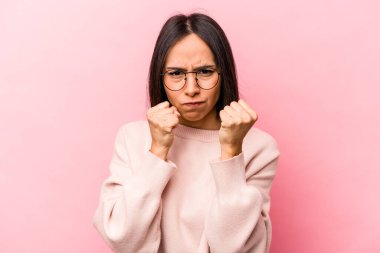 Pembe arka planda izole edilmiş genç İspanyol kadın kameraya yumruğunu, agresif yüz ifadesini gösteriyor..