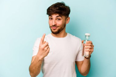 Beyaz arka planda izole edilmiş bir şişe su tutan İspanyol genç adam sanki seni davet ediyormuş gibi parmağıyla işaret ediyor..