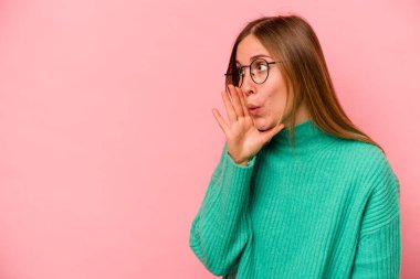 Pembe arka planda izole edilmiş genç beyaz kadın gizli bir sıcak fren haberi veriyor ve yana bakıyor.