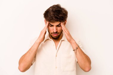 Beyaz arka planda izole edilmiş genç İspanyol bir adamın başı ağrıyor, yüzüne dokunuyor..