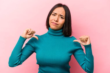 Pembe arka planda izole edilmiş genç İspanyol kadın baş parmağını aşağı gösteriyor, hayal kırıklığı konsepti.