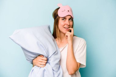 Mavi arka planda izole edilmiş pijama giyen genç beyaz kadın bir şeyin fotokopi odasına baktığını düşünerek rahatladı..