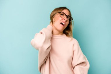 Mavi arka planda izole edilmiş genç beyaz kadın sabit yaşam tarzından dolayı boyun ağrısından muzdarip..