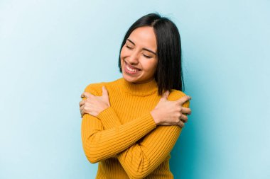 Mavi arka planda yalnız yaşayan genç İspanyol kadın gülüyor ve eğleniyor..