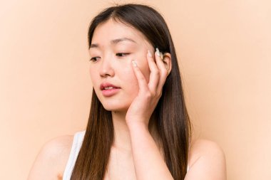 Genç bir Asyalı kadın bej arka planda izole edilmiş.