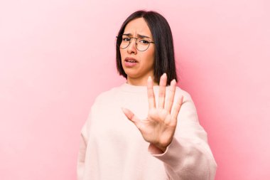 Pembe arka planda izole edilmiş genç İspanyol kadın yakın bir tehlike nedeniyle şoka uğruyor.