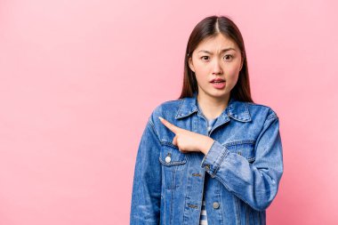 Pembe arka planda izole edilmiş genç Çinli kadın yan tarafı gösteriyor.