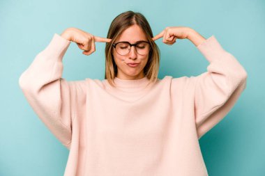 Kafkasyalı genç bir kadın mavi arka planda izole edilmiş bir vazifeye odaklanmış, parmaklarını işaret ediyor..