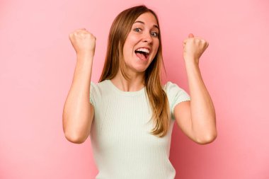 Pembe arka planda soyutlanmış, tasasız ve heyecanlı genç bir beyaz kadın. Zafer konsepti.