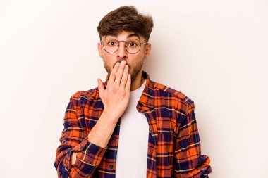 Beyaz arka planda izole edilmiş genç İspanyol adam şok olmuş, ağzı ellerle kaplanmış, yeni bir şey keşfetmeye hevesli..