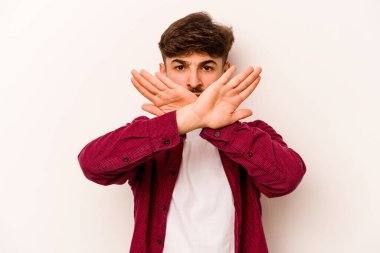 Beyaz arka planda izole edilmiş genç İspanyol bir adam inkar jesti yapıyor.