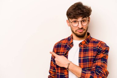 Beyaz arka planda izole edilmiş genç İspanyol adam gülümsüyor ve boş alanda bir şeyler gösteriyor..